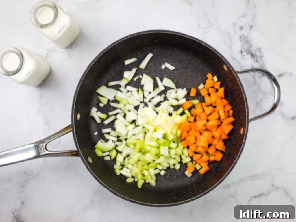 A frying pan with carrots, onions and celery.