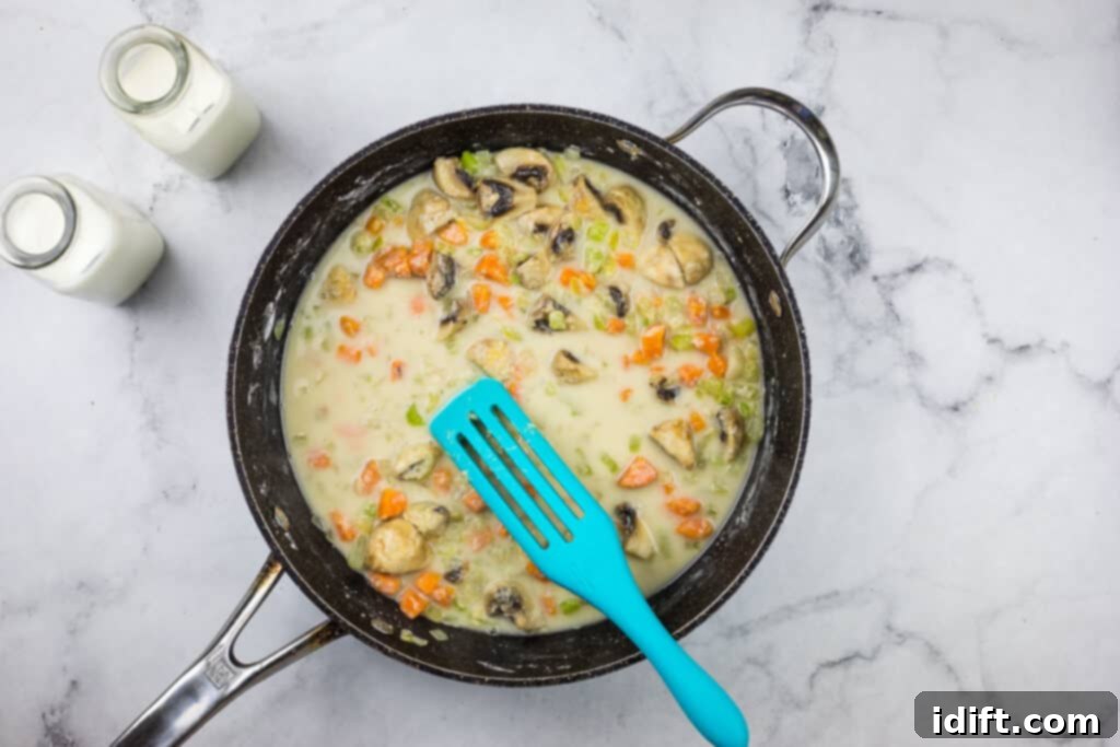 A skillet with mushrooms and milk in it.