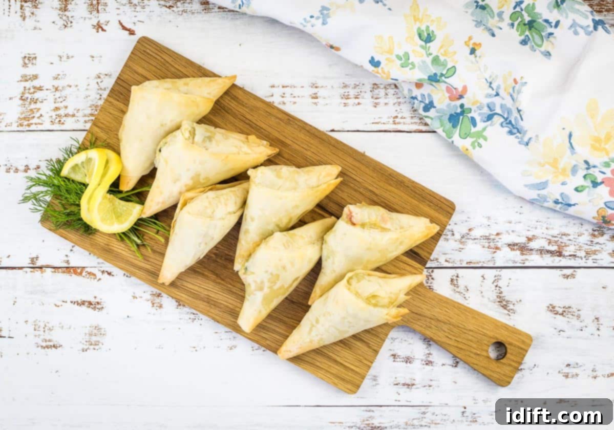 Crab Spanakopita triangles on a cutting board.