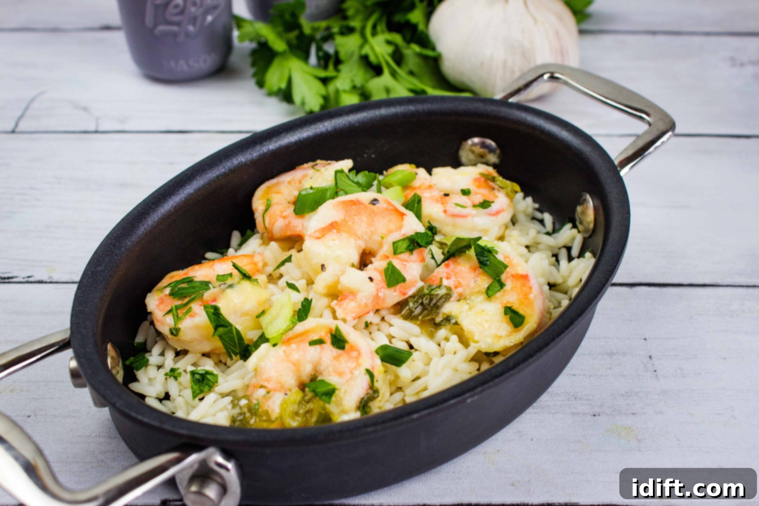 A delectable dish of Garlic Shrimp Scampi, presented on a bed of rice in an elegant black oval dish.