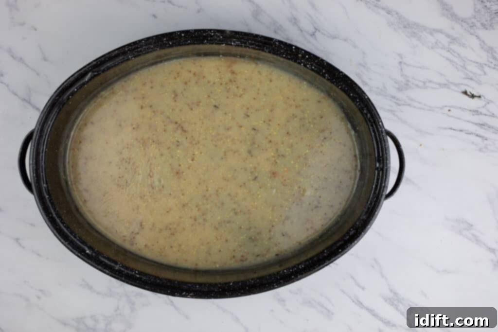 A pot of rich, simmering gravy on a stovetop, being whisked to perfection, with a creamy texture visible.