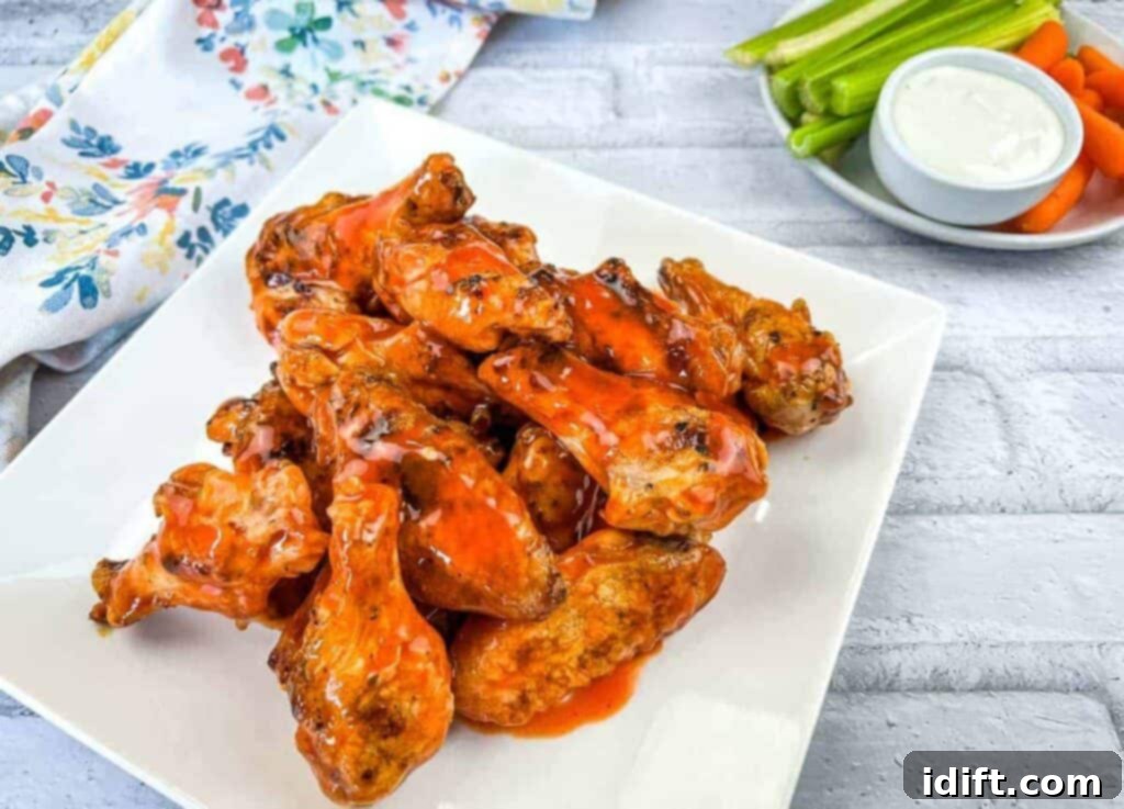 11 Recipes to Ignite Your Spice Obsession 6 Buffalo wings on a white plate with carrots and celery.