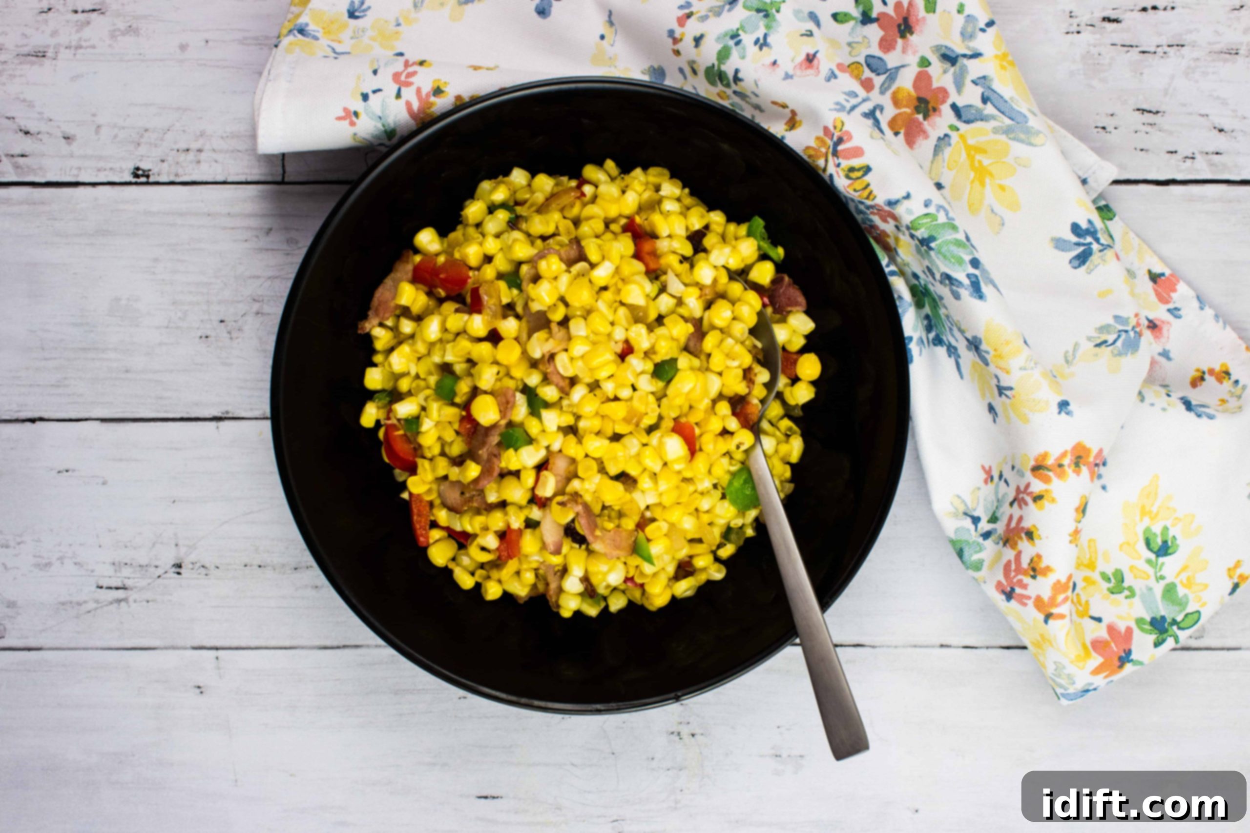 Texas Corn Succotash in a black bowl, featuring colorful corn, beans, and peppers.