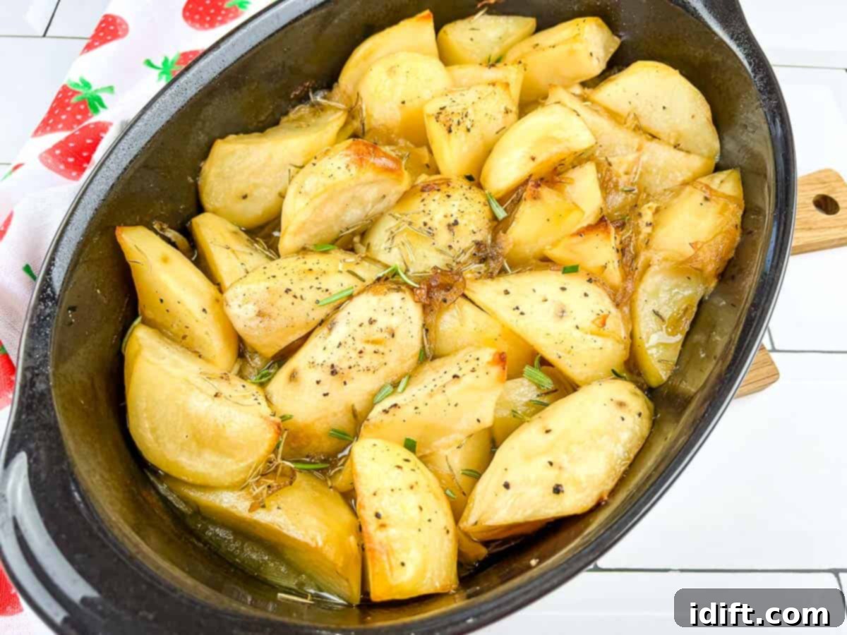 Braised potatoes in a pan after cooking, glistening with herbs and garlic.