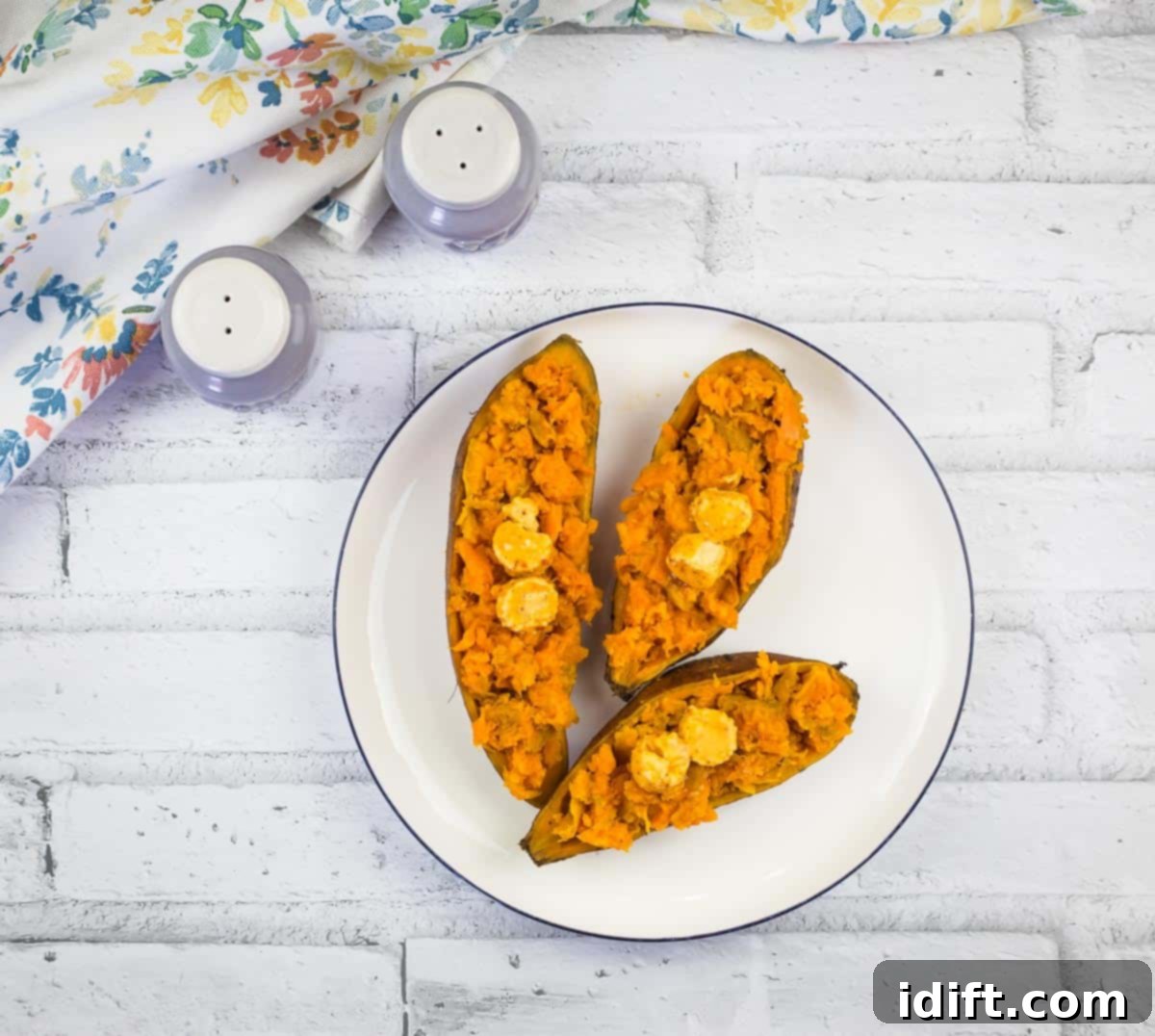 Smoked Sweet Potatoes with Chipotle Butter on a round white plate, showing a rich, caramelized exterior.