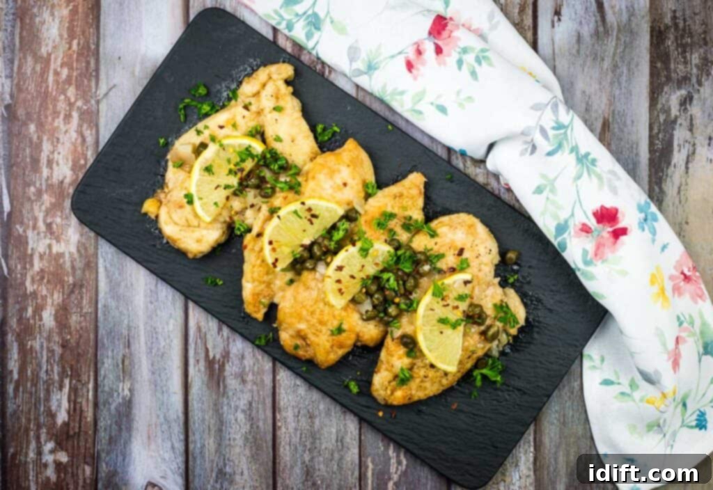 17 Foolproof Family Dinners Everyone Loves 3 Two chicken piccata on a white plate with parsley and lemon wedges.