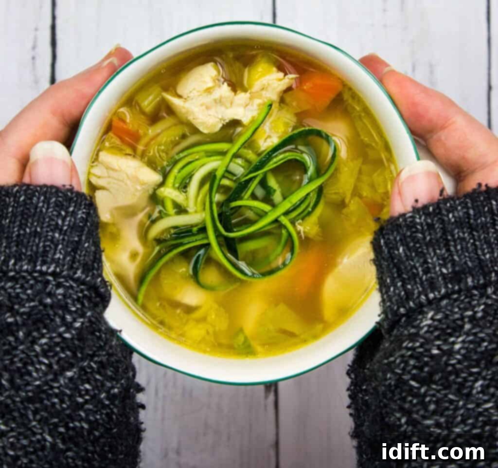 17 Foolproof Family Dinners Everyone Loves 4 A person holding a bowl of chicken and zucchini soup.