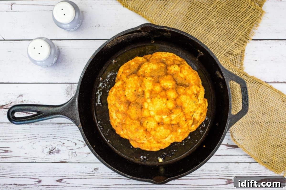 11 Recipes That Will Seriously Impress Him With Your Cooking 5 Smoked cauliflower in a rustic skillet on a wooden table, showcasing its golden-brown exterior.