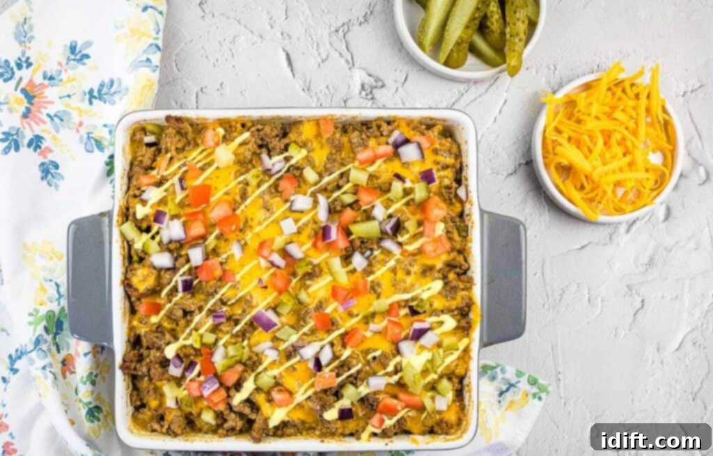 Cheeseburger Casserole in a baking dish with pickles and cheese nearby.