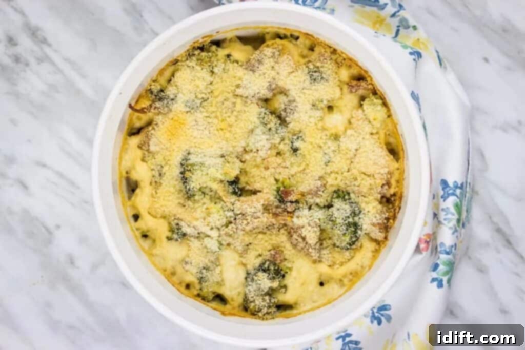A white dish with broccoli and cheese in it.