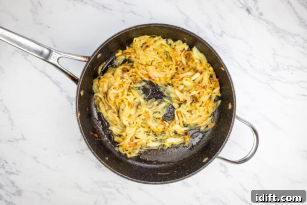 Chef Jenn's Signature French Onion Soup 7 Partially fried onions in a skillet on a marble countertop, beginning to turn golden.