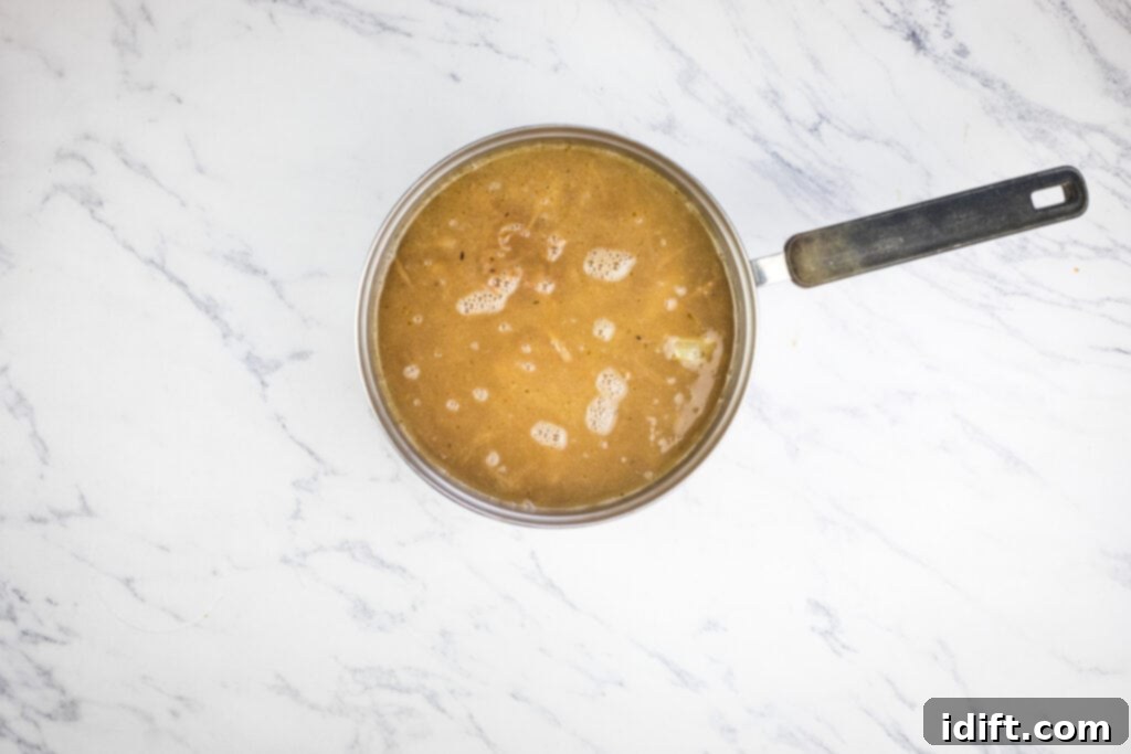 Chef Jenn's Signature French Onion Soup 9 A pan full of onion soup on a marble countertop, after adding broth and simmering.