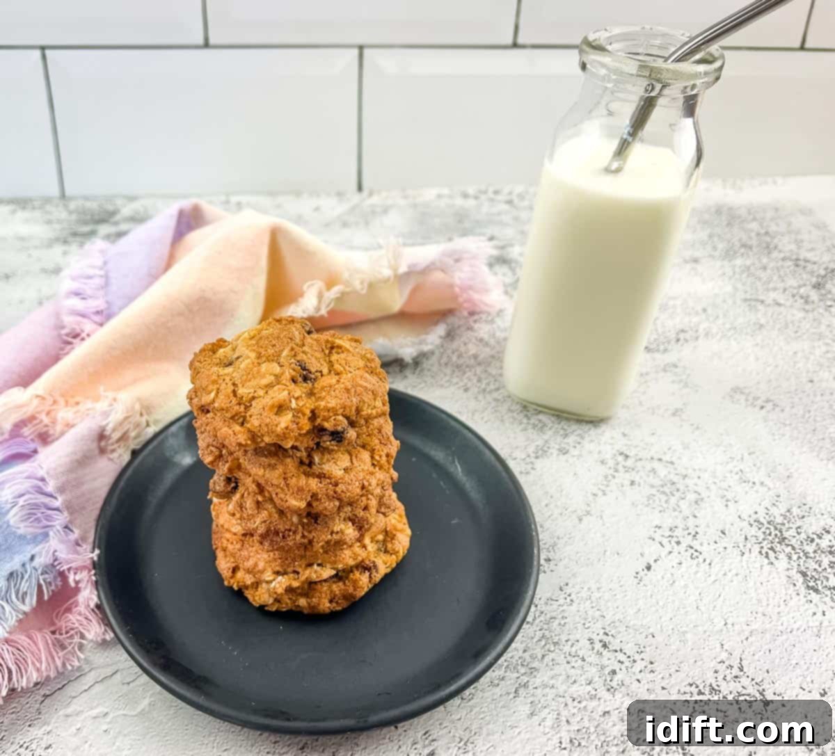 Oatmeal raisin cookies on a plate next to a glass of milk.