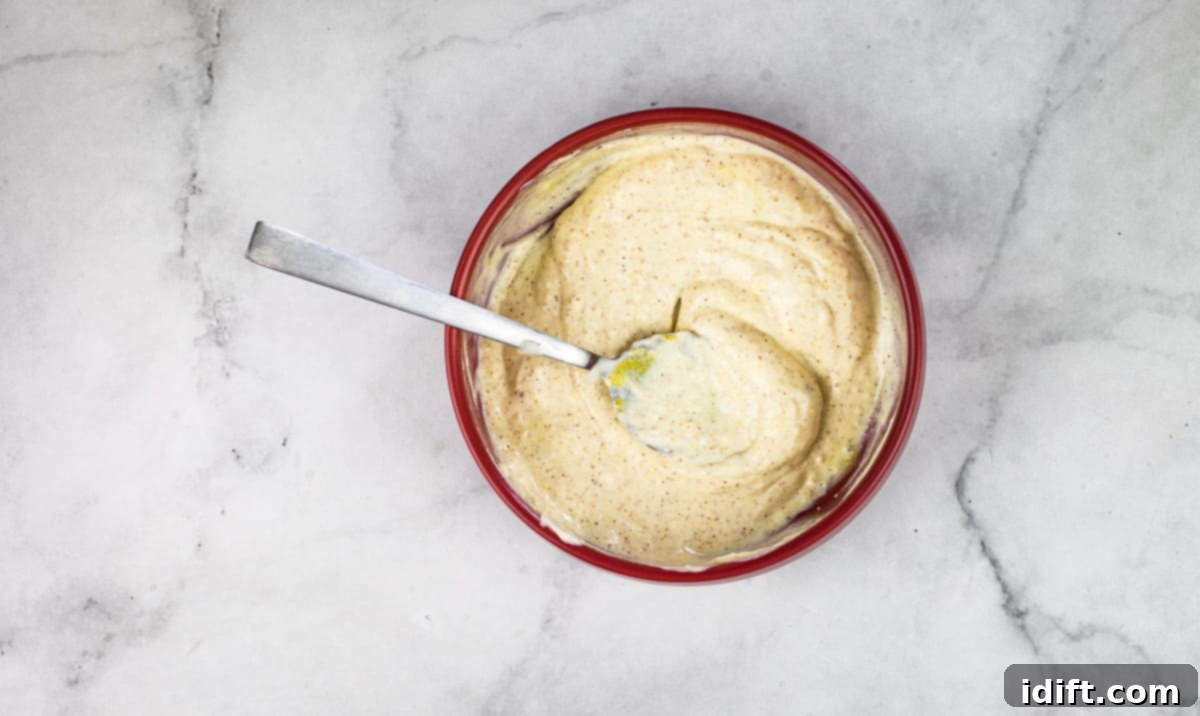 A bowl of garlic aioli dip with a clove of garlic next to it.