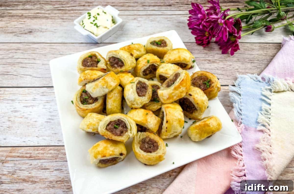 Golden-brown Sausage Rolls, fresh from the oven, elegantly presented on a pristine white plate.