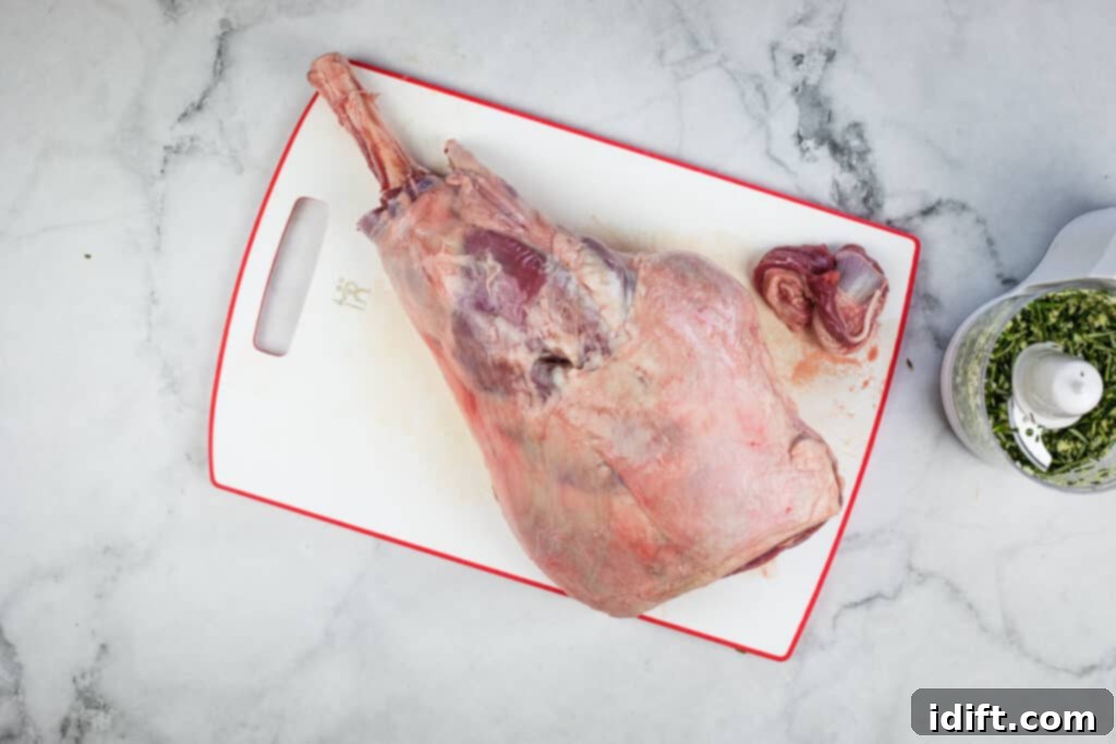 Using a knife to gently pull away meat and sinew from the lamb bone, exposing it.