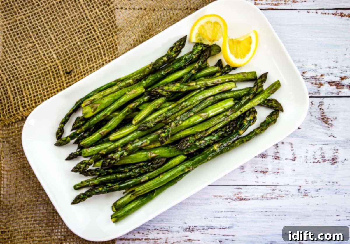 Smoked asparagus on a white platter with lemon.