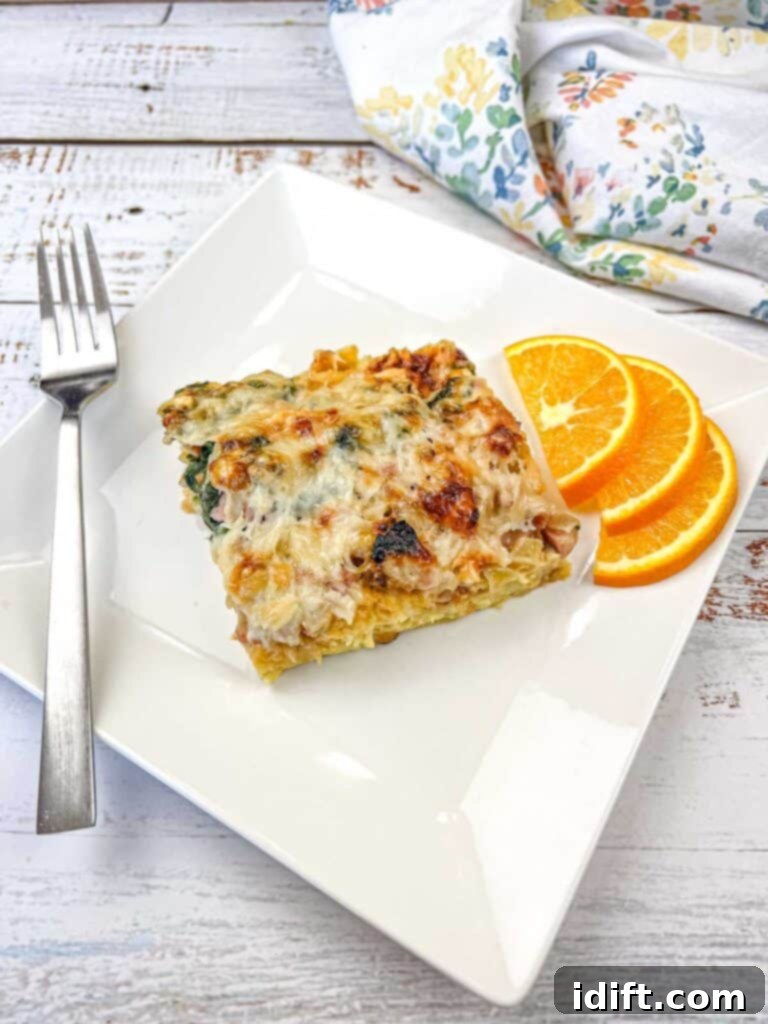 Fluffy Croissant Breakfast Delight 2 A slice of breakfast casserole on a white plate with orange slices.