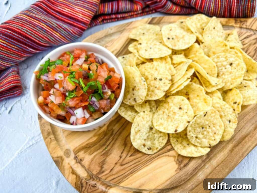 19 Snacks So Good, One Is Never Enough 12 Fresh Pico de Gallo salsa and crispy tortilla chips artfully arranged on a rustic wooden cutting board.
