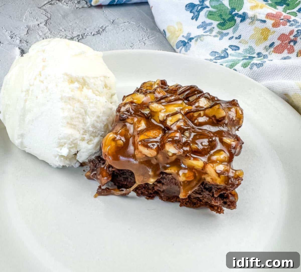 11 Desserts So Easy You Wont Believe It 2 A generous slice of Turtle Brownie, rich with chocolate, caramel, and pecans, served alongside a scoop of vanilla ice cream on a white plate, offering a perfect blend of warm and cold textures.