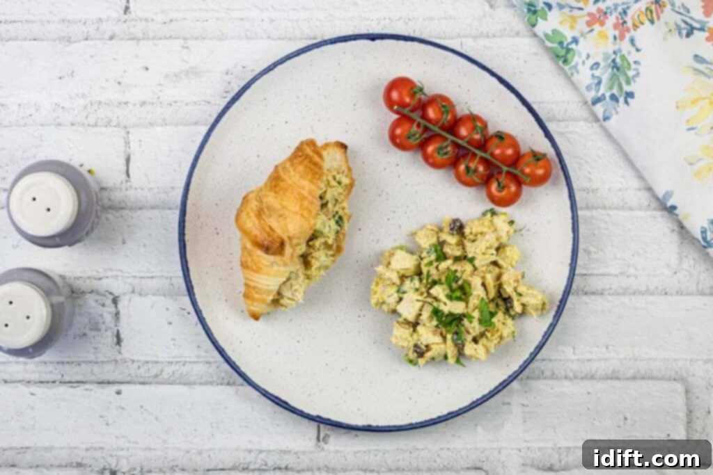 Regal Curried Chicken Salad 3 A plate with a croissant, Coronation Chicken Salad, and tomatoes.