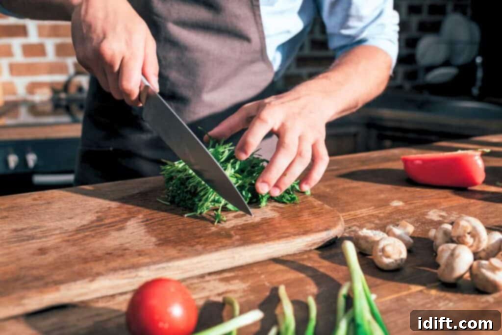 A man is chopping vegetables on a wooden cutting board.