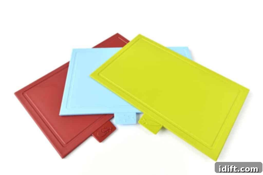 Three colorful plastic cutting boards on a white surface.