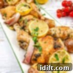 Roasted chicken with lemons and potatoes on a white plate.