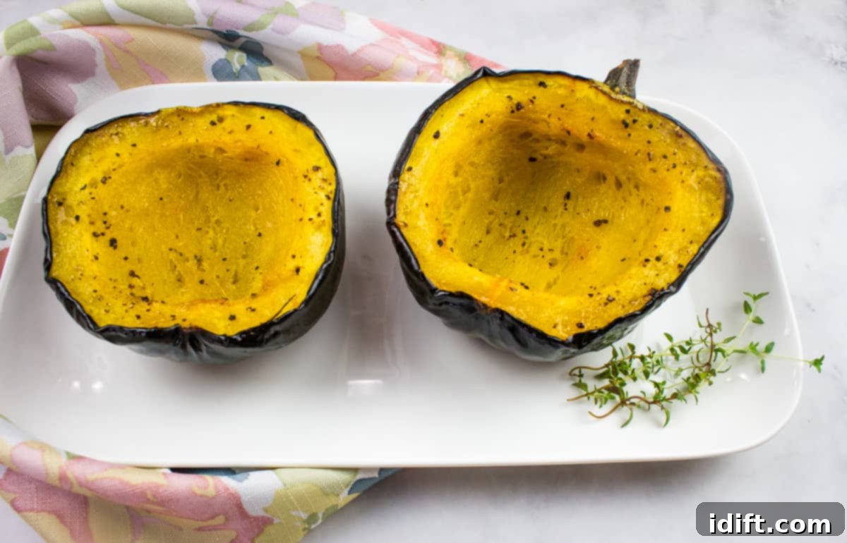 Two perfectly halved baked acorn squash, glistening with a generous drizzle of golden maple syrup and delicately seasoned with warming spices, elegantly served on a pristine white plate.