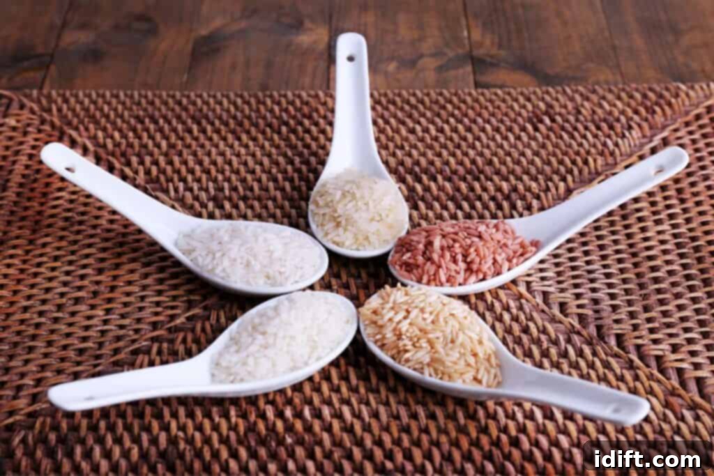 Assortment of different types of rice displayed on white spoons over a textured woven mat, showcasing various colors and grain lengths.