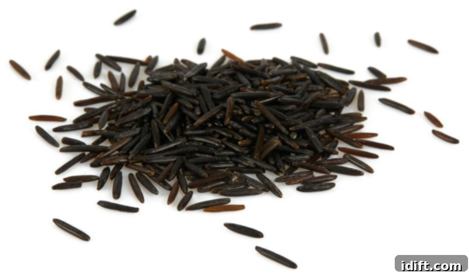 A generous pile of dark, slender wild rice grains displayed on a clean white background.