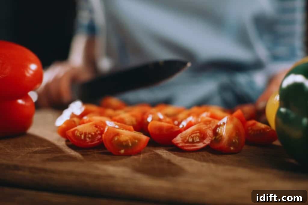 Tomato Bounty: Your Comprehensive Guide to Varieties and Tastes 3 A person expertly slicing bright red cherry tomatoes on a wooden cutting board with a sharp knife, amidst a colorful array of fresh vegetables, emphasizing the act of preparing healthy food.