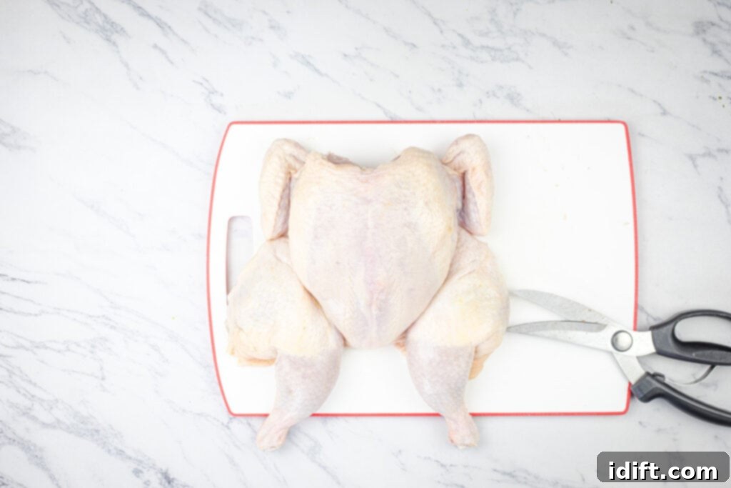 Mastering Spatchcock Chicken 2 Whole raw chicken on a cutting board with kitchen shears, ready for spatchcocking.