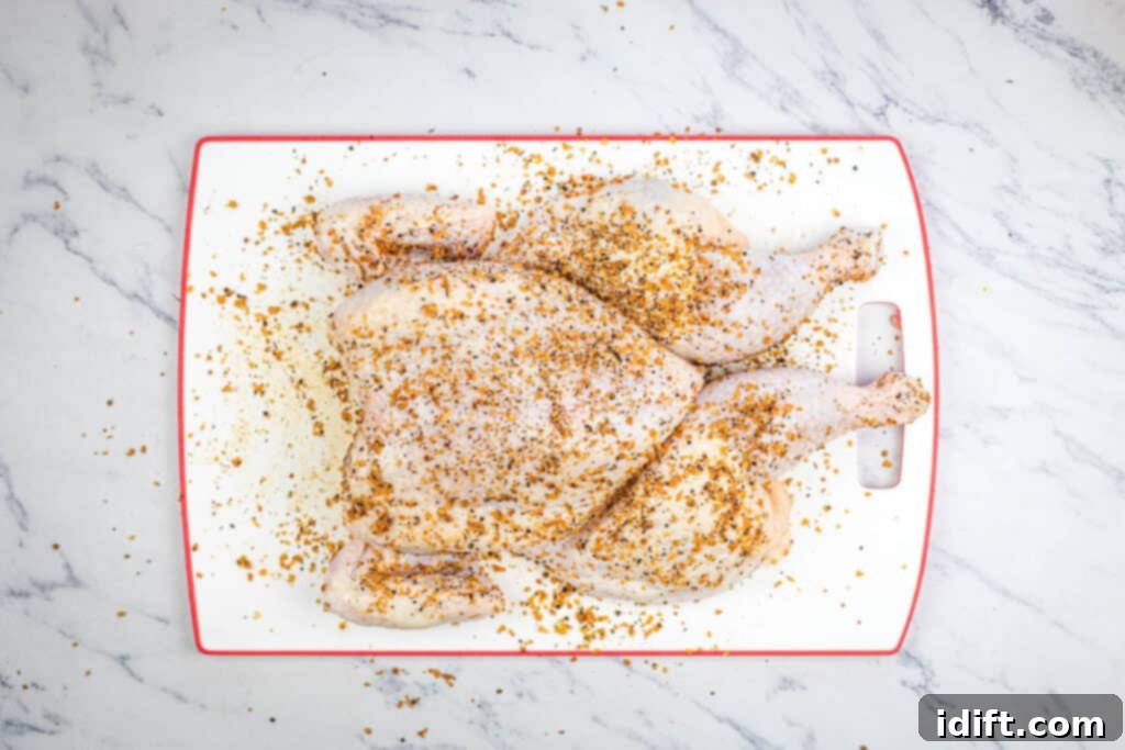 Mastering Spatchcock Chicken 7 A raw chicken spatchcocked and seasoned on a cutting board, ready for cooking.