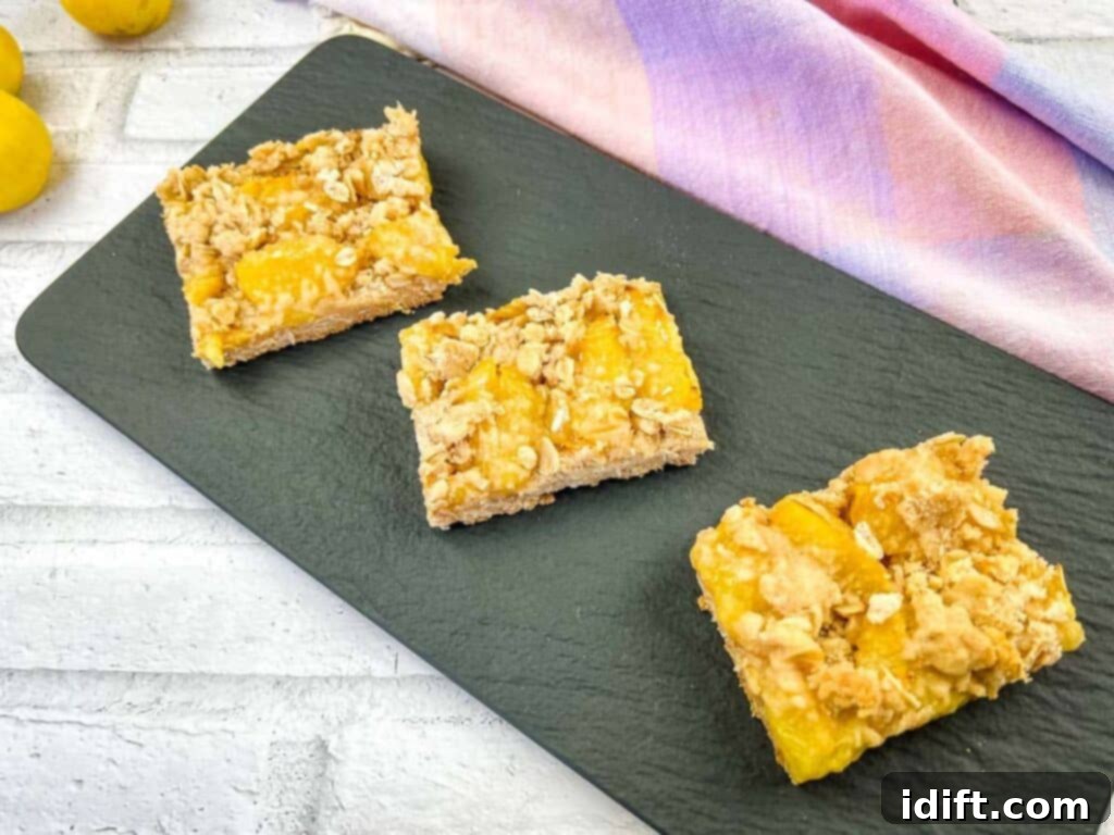 Four golden-brown lemon crumb bars, simple yet elegant, arranged on a dark black slate.