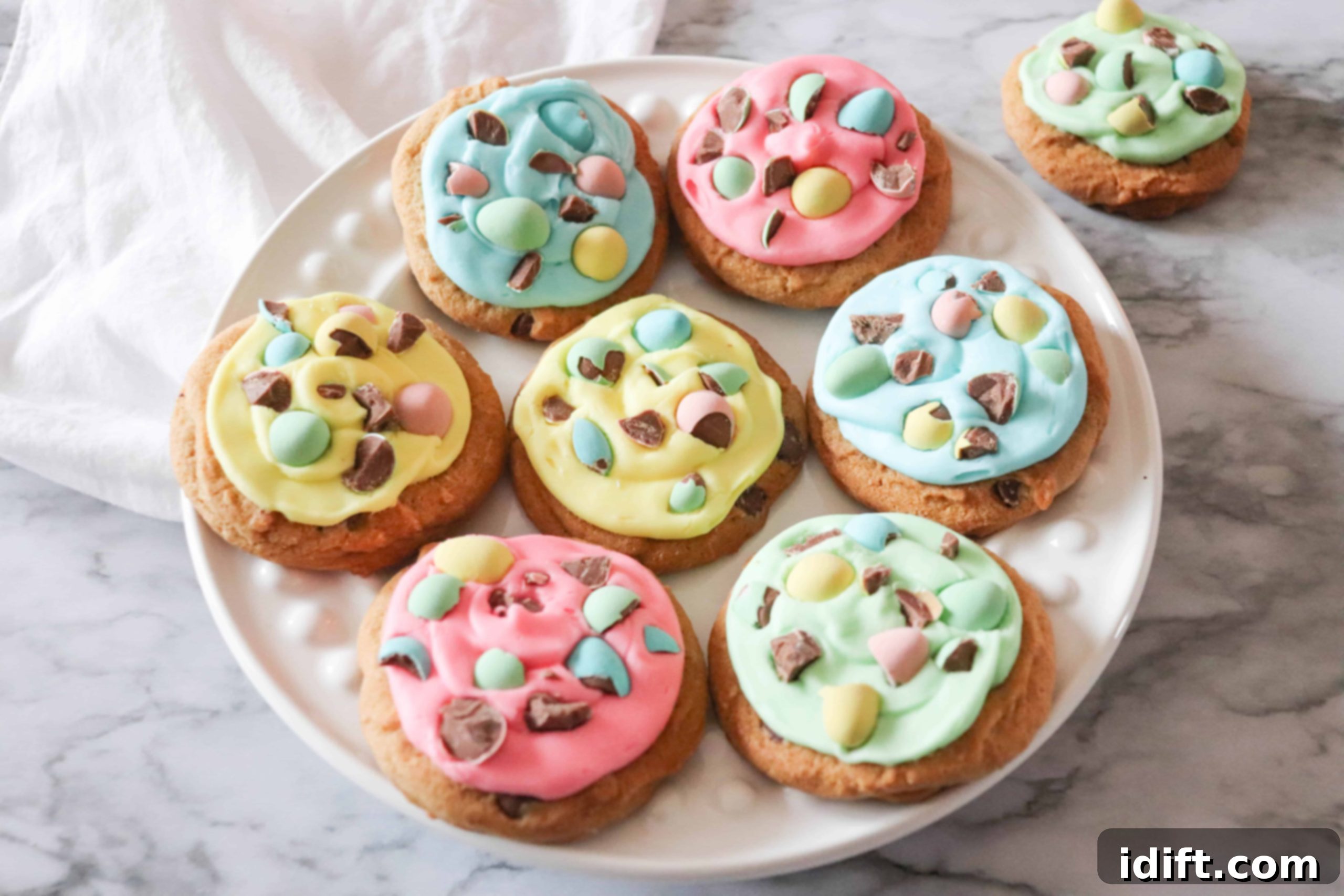 Mini egg cookies on a white plate with colorful icing.