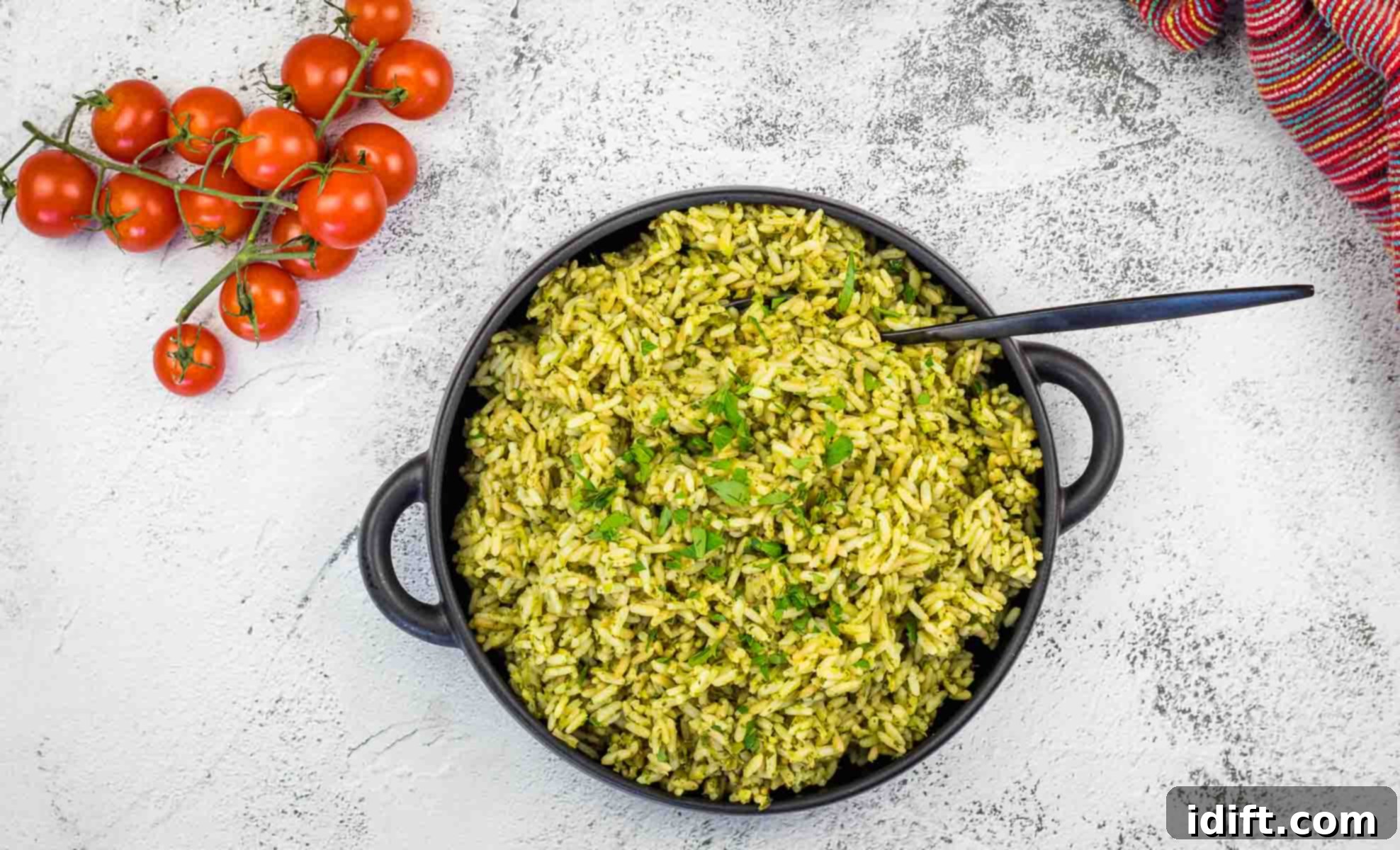 Arroz Verde rice in a black pan with tomatoes and herbs.