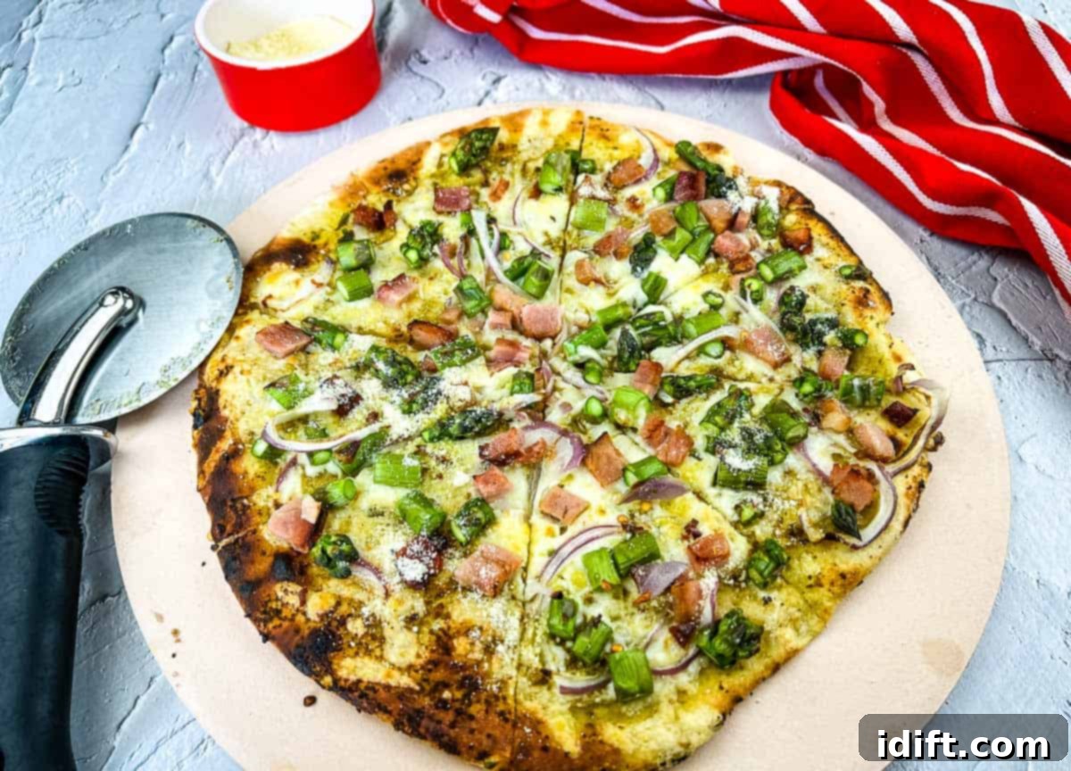 A gourmet Ham & Asparagus Pizza freshly baked on a rustic pizza stone, showcasing vibrant toppings.