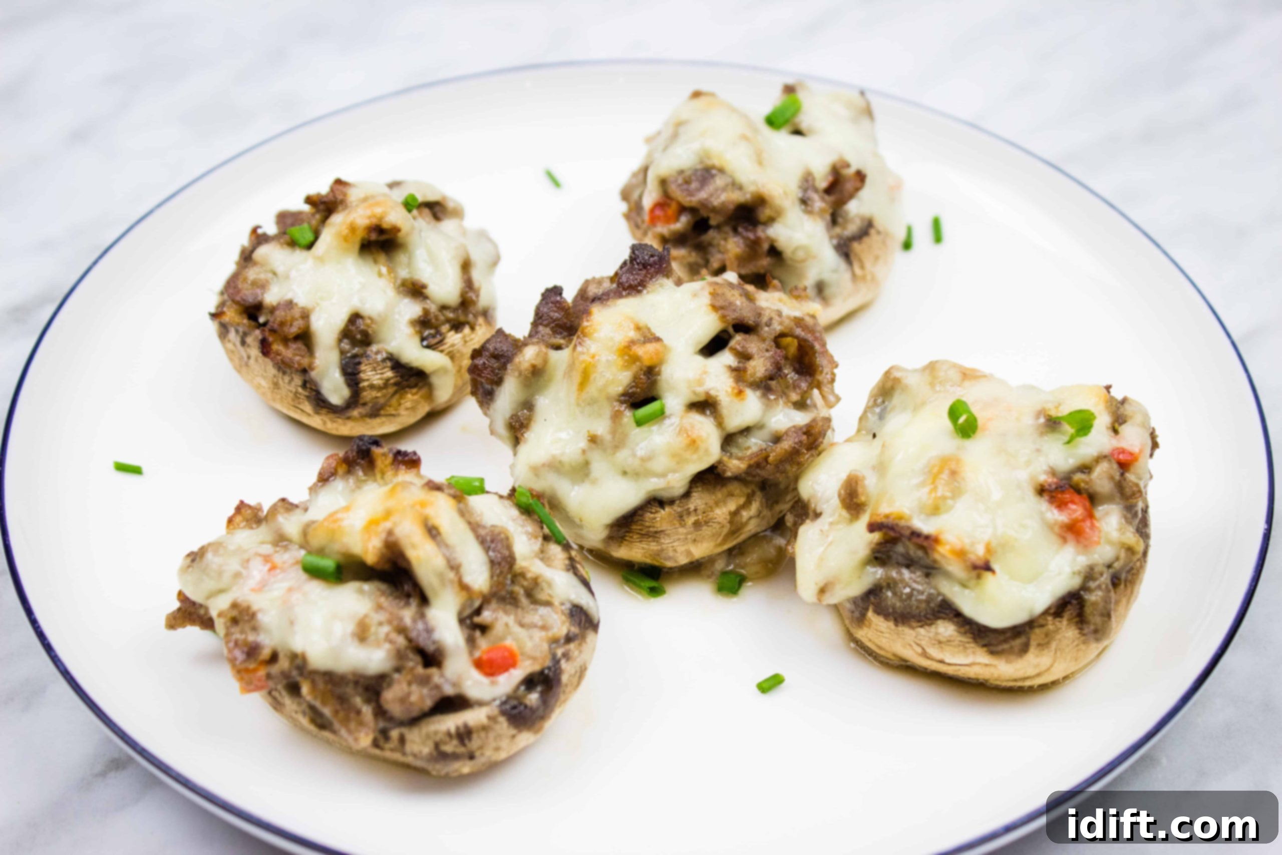 Four stuffed mushrooms on a white plate.