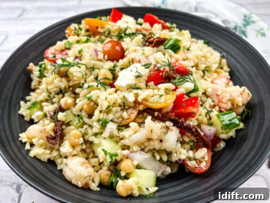A bowl of Mediterranean orzo salad on a black plate.