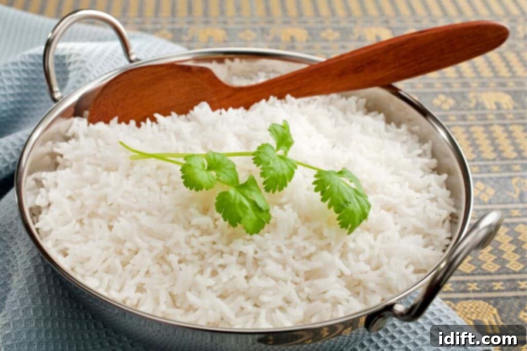Cook Basmati Like A Chef Achieve Fluffy Perfection 2 Basmati rice in a steel karahi, garnished with coriander, with a wooden spoon.