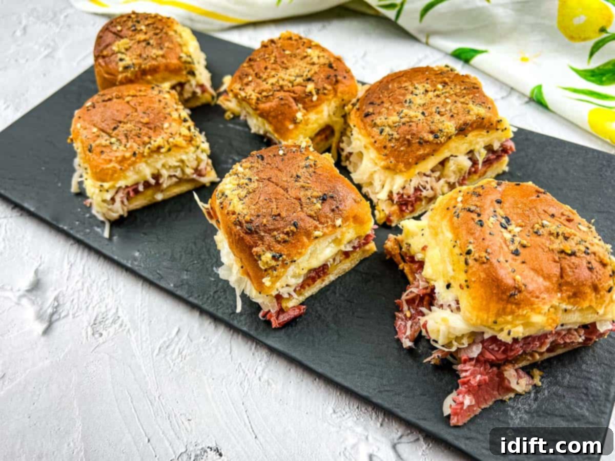 Reuben sliders arranged on a slate board, featuring corned beef, Swiss cheese, sauerkraut, and Russian dressing for a delightful quick lunch.