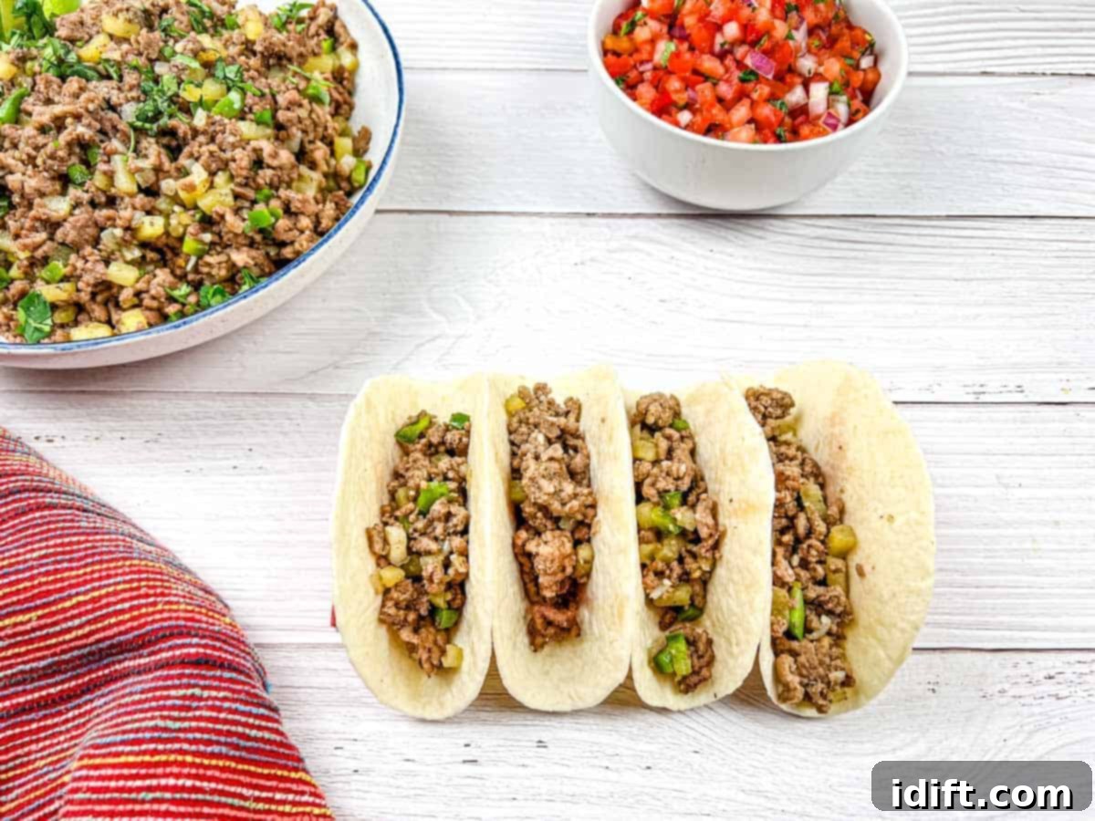 Four tacos with Mexican molida on a wooden table.