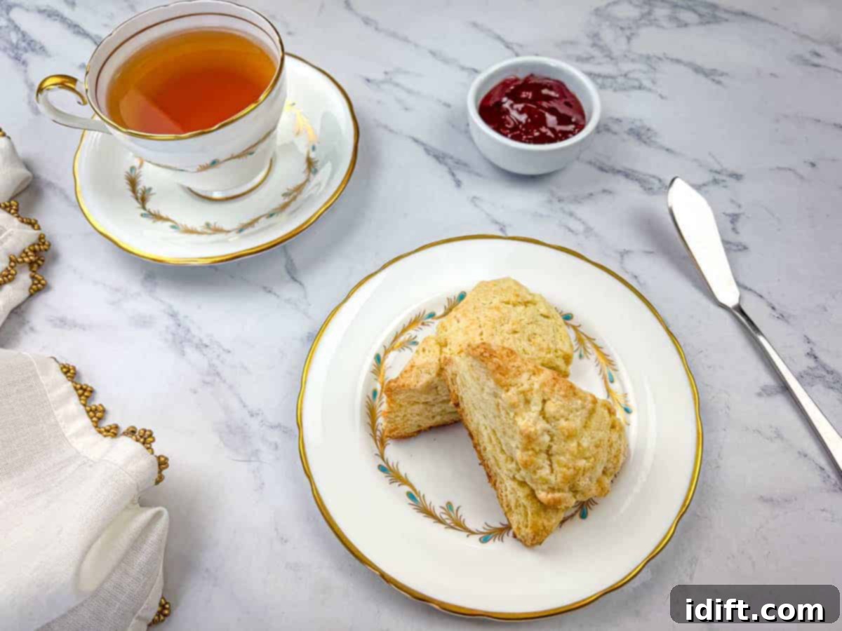 13 Desserts Too Good for Sharing 6 Two butter scones on a plate with a cup of tea on a marble surface.