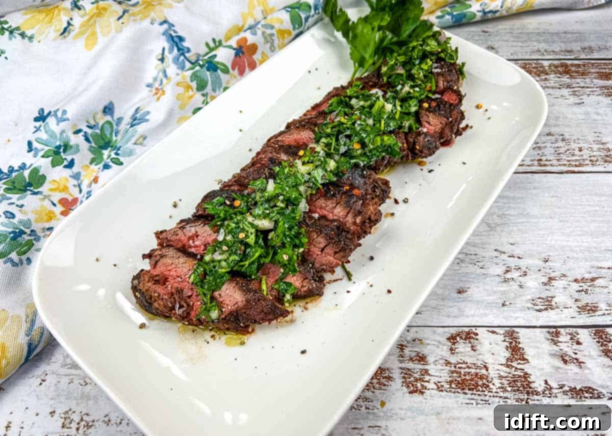 Sliced Grilled Hanger Steak with fresh green Chimichurri sauce on a white plate.