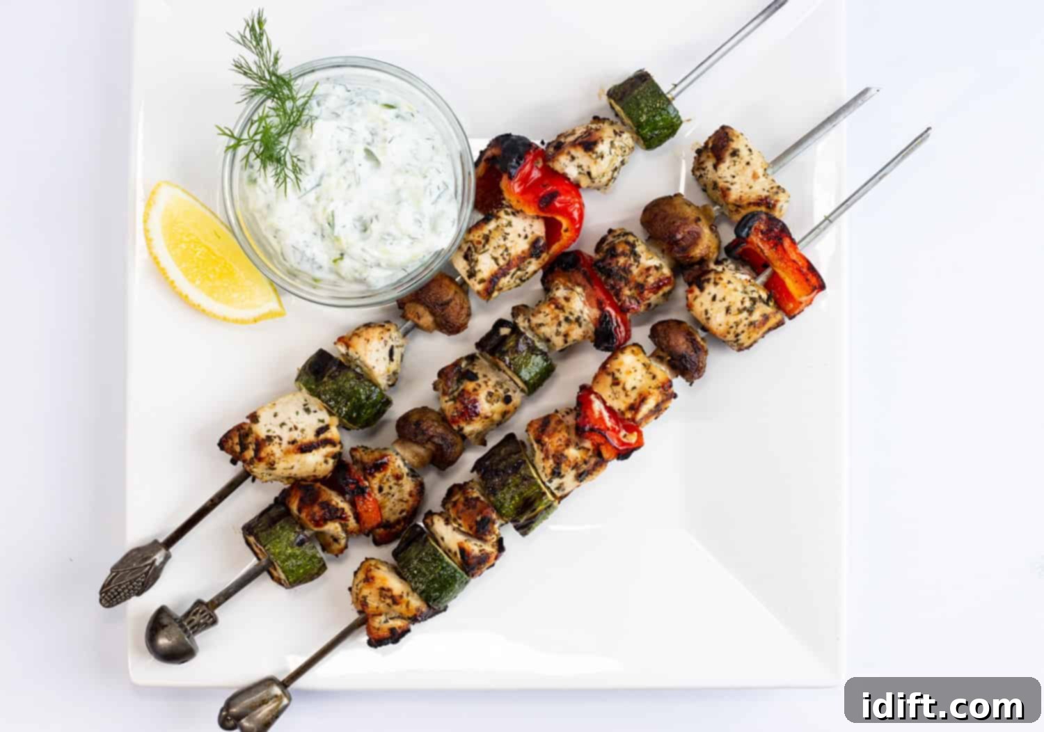 Grilled Lemon-Oregano Chicken Kabobs with a dipping sauce and fresh herbs.