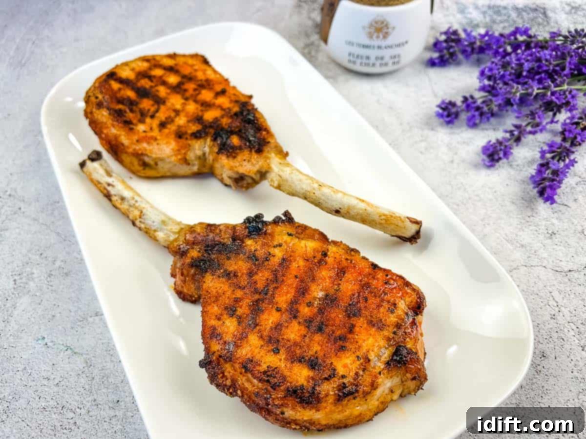 Taste The Heat: 17 Grilling Recipes To Ignite Your Weekend 5 Impressive Grilled Pork Tomahawk Chops, showcasing their majestic bone-in presentation, resting on a clean white plate.