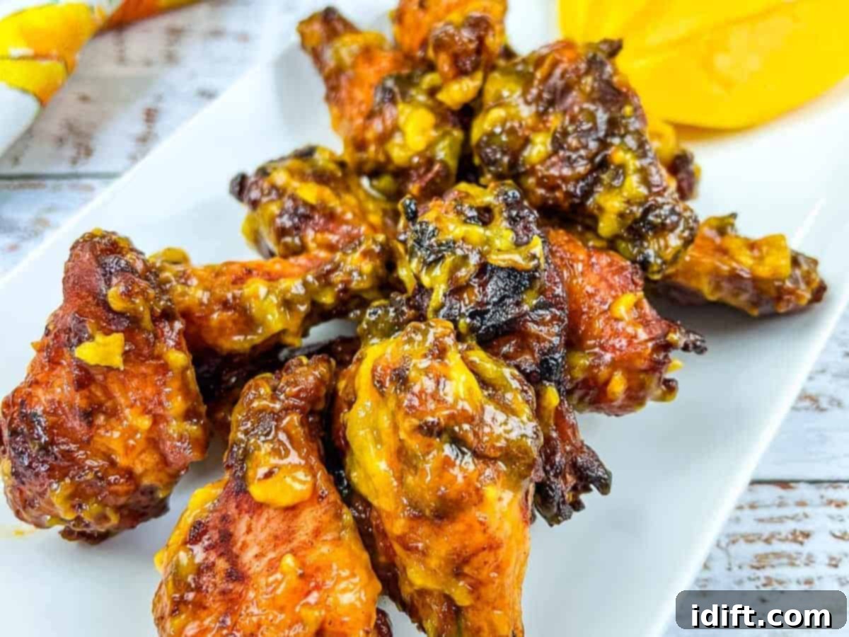 Taste The Heat: 17 Grilling Recipes To Ignite Your Weekend 7 A vibrant plate of Grilled Mango-Chipotle Chicken Wings, garnished with a fresh mango slice, showcasing their irresistible glaze and smoky char.