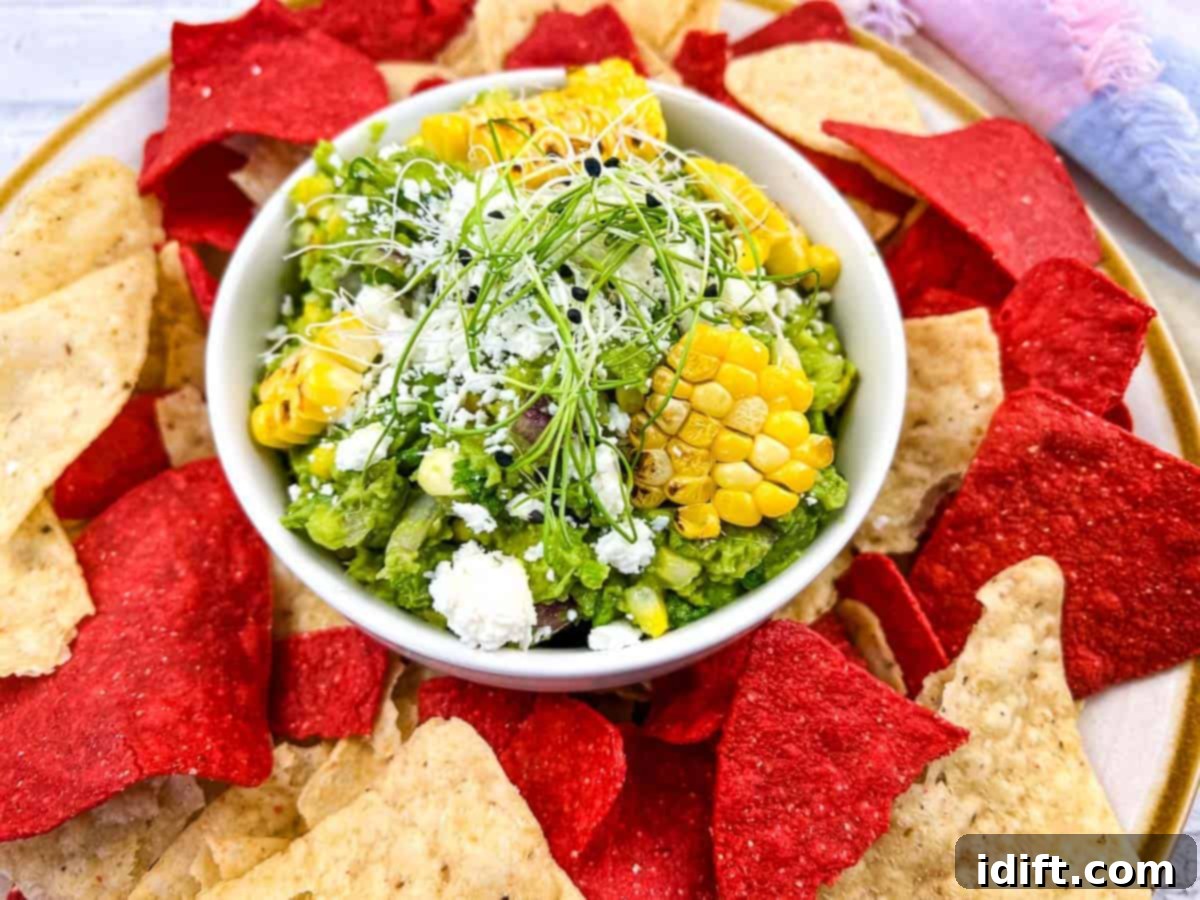 Grilled Corn Guacamole served with crispy tortilla chips on a vibrant plate.