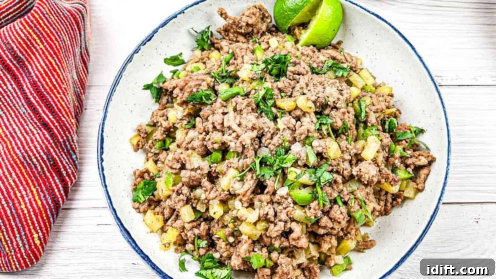 17 Ground Beef Recipes Too Good For Cookbooks 12 A close-up of Carne Molida, Mexican ground beef mixed with diced vegetables, garnished with lime wedges and cilantro.